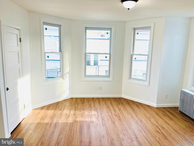 unfurnished room with light wood-type flooring and radiator heating unit