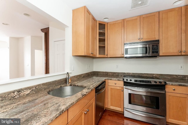 kitchen with dark wood-type flooring, sink, stone counters, and stainless steel appliances