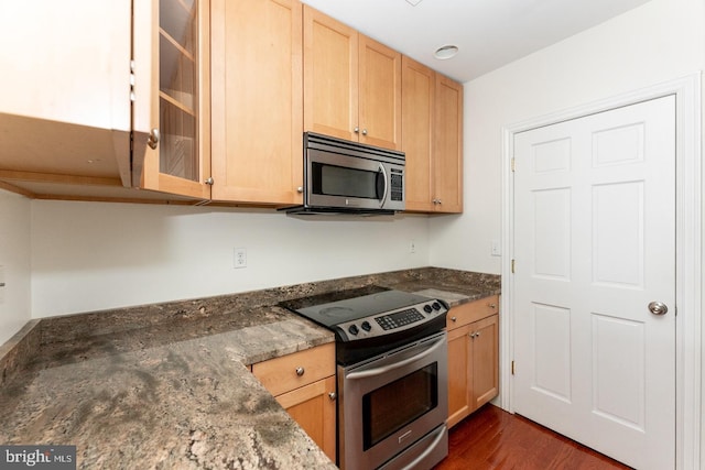 kitchen with dark hardwood / wood-style flooring, dark stone countertops, light brown cabinetry, and appliances with stainless steel finishes