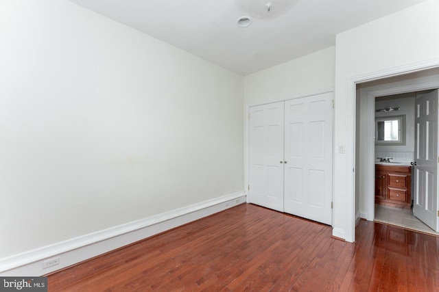 unfurnished bedroom with a closet, dark hardwood / wood-style flooring, and sink