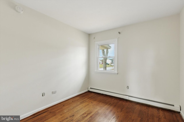 spare room featuring baseboard heating and hardwood / wood-style flooring