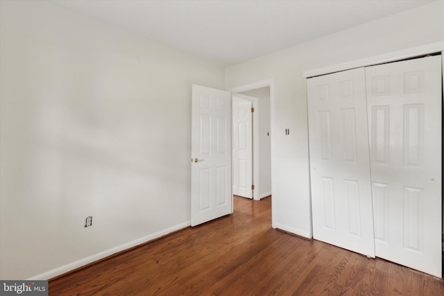 unfurnished bedroom featuring dark hardwood / wood-style flooring and a closet