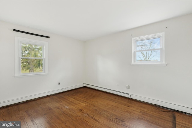 spare room with dark hardwood / wood-style flooring, a baseboard radiator, and a wealth of natural light