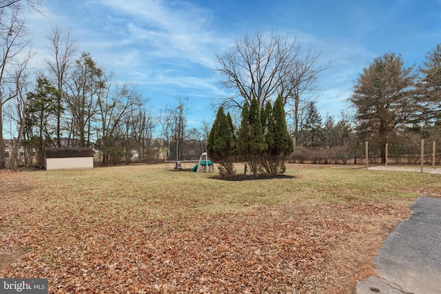 view of yard featuring a trampoline and a storage shed