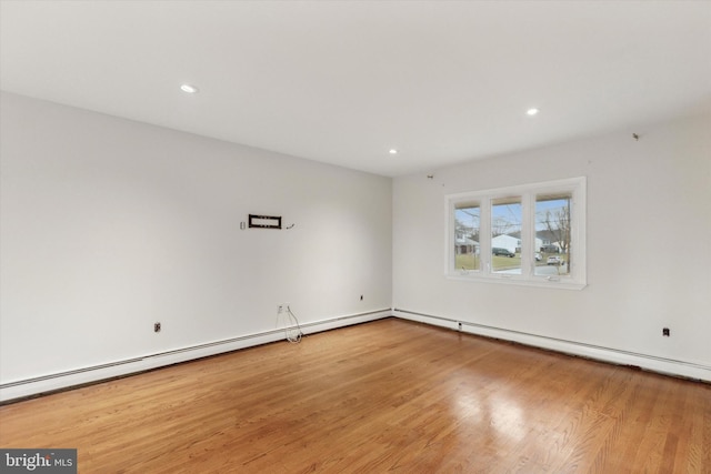 spare room featuring a baseboard heating unit and hardwood / wood-style flooring