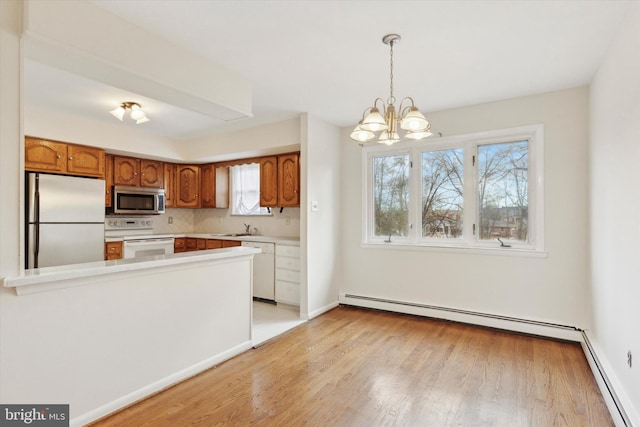 kitchen with pendant lighting, decorative backsplash, a baseboard heating unit, an inviting chandelier, and appliances with stainless steel finishes