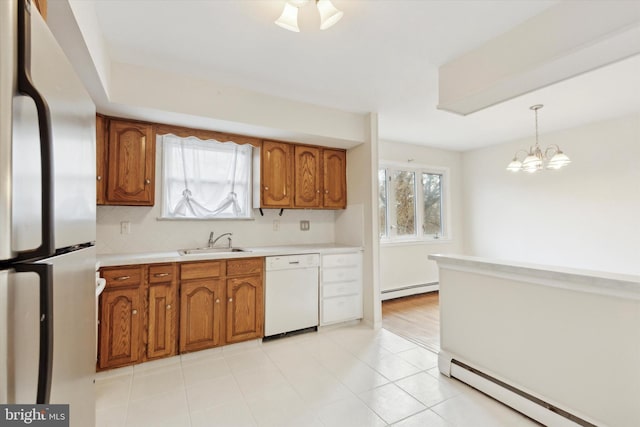 kitchen with sink, white dishwasher, stainless steel refrigerator, a baseboard radiator, and pendant lighting