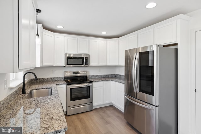 kitchen featuring sink, stainless steel appliances, white cabinetry, and light stone counters