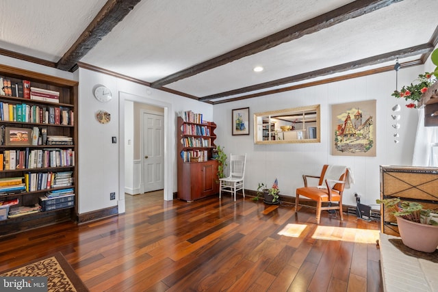 living area with beam ceiling, dark hardwood / wood-style flooring, ornamental molding, and a textured ceiling