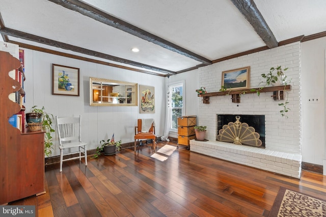 living area with dark hardwood / wood-style flooring, a textured ceiling, a fireplace, and beamed ceiling