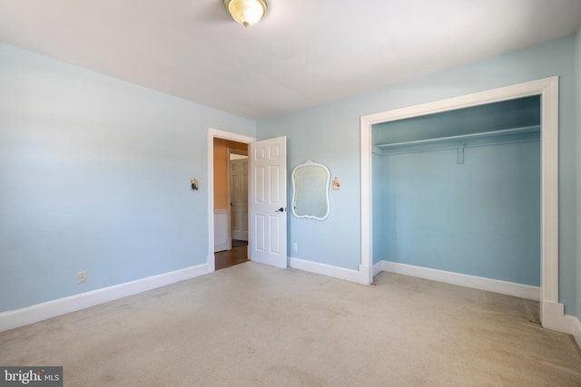 unfurnished bedroom with light colored carpet and a closet