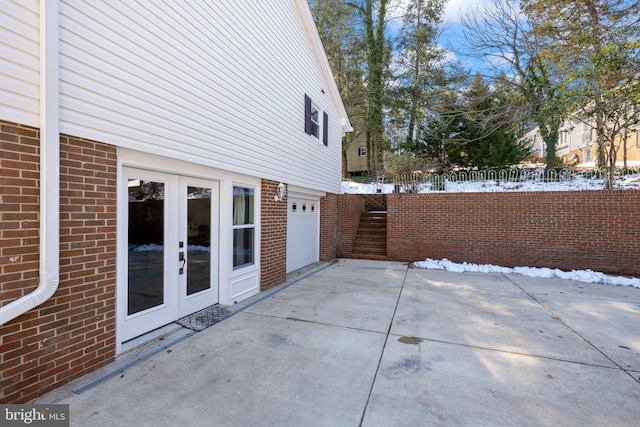 snow covered patio featuring french doors and a garage