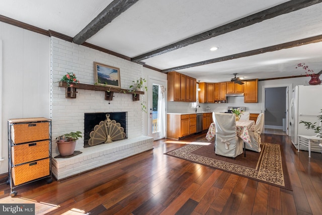 interior space featuring a fireplace, beamed ceiling, sink, ceiling fan, and dark wood-type flooring