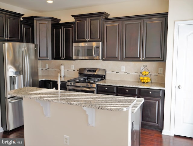 kitchen with stainless steel appliances, a kitchen bar, dark hardwood / wood-style floors, and a center island