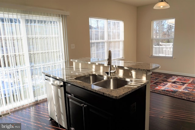 kitchen featuring light stone countertops, dishwasher, sink, and a center island with sink