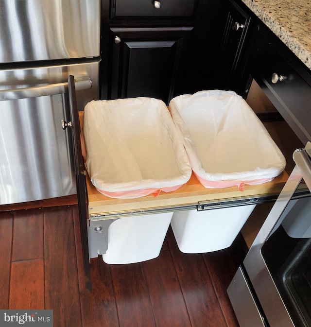 interior details with stove, refrigerator, light stone counters, and hardwood / wood-style floors