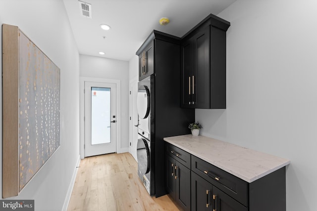 interior space featuring stacked washing maching and dryer, cabinets, and light wood-type flooring