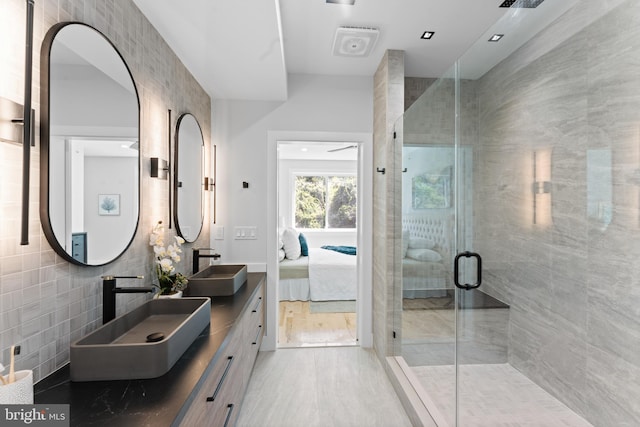 bathroom with vanity, tile walls, and a shower with shower door