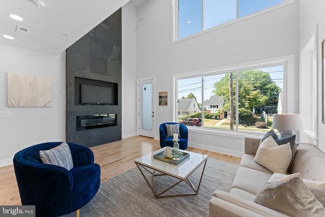 living room featuring a high ceiling, hardwood / wood-style flooring, and a fireplace