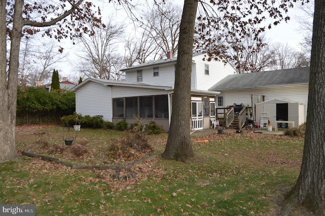 back of house featuring a sunroom, a shed, and a lawn