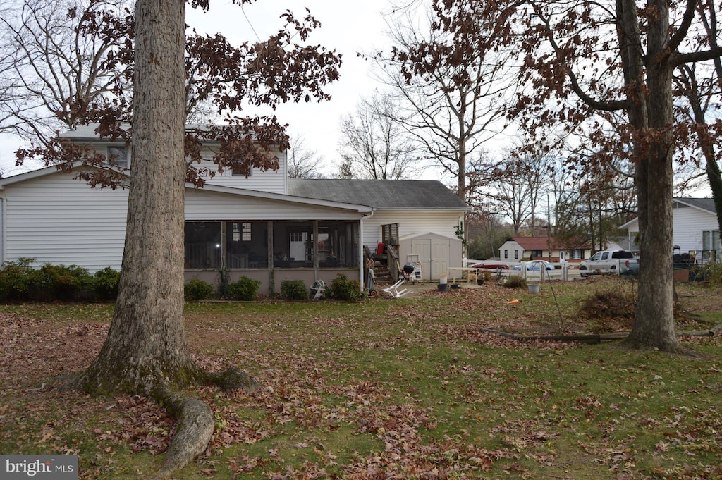 back of house featuring a sunroom, a yard, and a storage unit