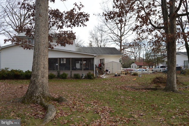 back of property featuring a sunroom, a yard, and a shed