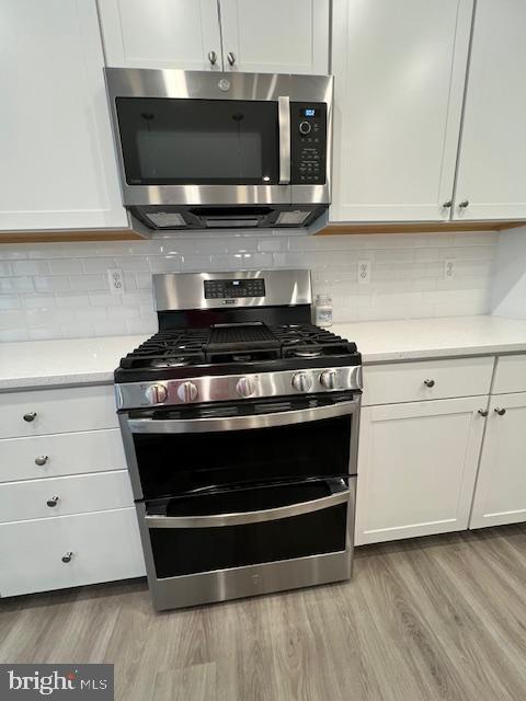 kitchen featuring stainless steel appliances, light hardwood / wood-style flooring, and white cabinetry