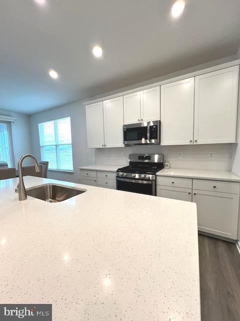 kitchen featuring decorative backsplash, sink, light stone countertops, appliances with stainless steel finishes, and white cabinets