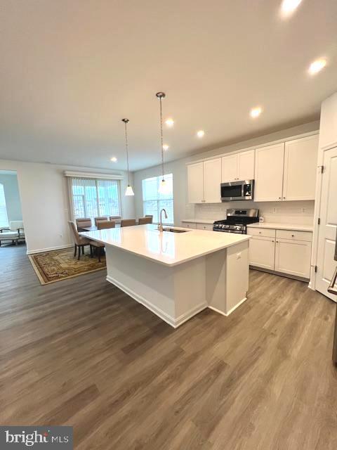 kitchen featuring a center island with sink, stainless steel appliances, dark hardwood / wood-style floors, white cabinets, and sink