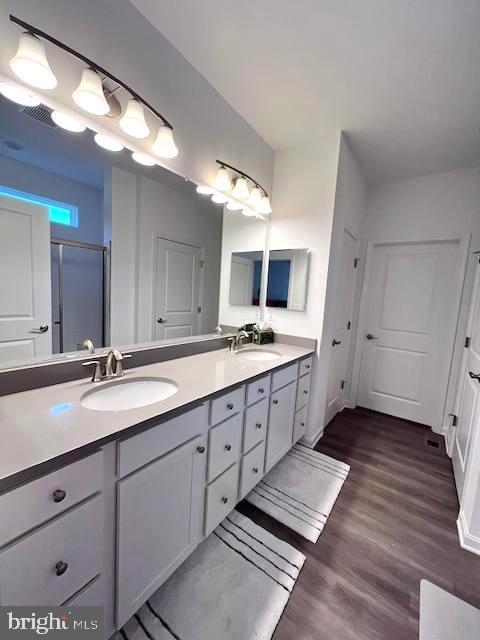 bathroom with walk in shower, wood-type flooring, and vanity