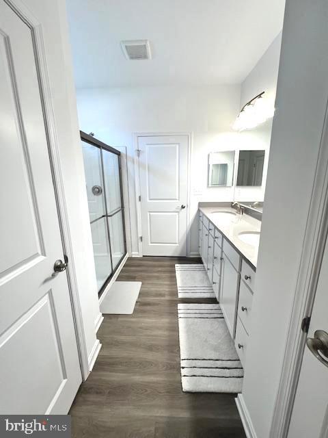 bathroom with an enclosed shower, vanity, and hardwood / wood-style flooring