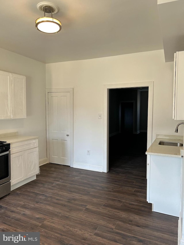 kitchen with sink, white cabinetry, stove, and dark hardwood / wood-style floors