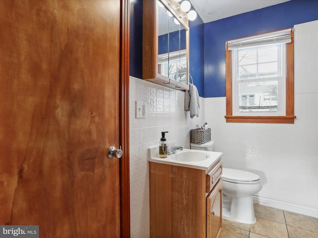 bathroom with toilet, vanity, tile patterned floors, and tile walls