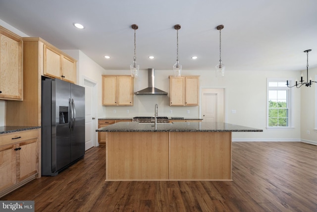 kitchen featuring dark hardwood / wood-style flooring, an island with sink, stainless steel fridge, and wall chimney exhaust hood