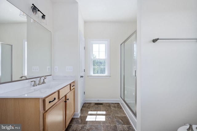 bathroom featuring a shower with door and vanity