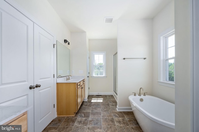 bathroom with vanity, a healthy amount of sunlight, and plus walk in shower