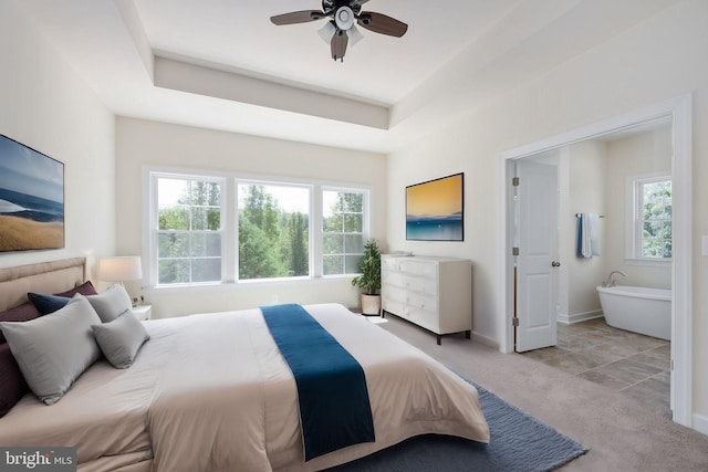 carpeted bedroom featuring ceiling fan and a raised ceiling