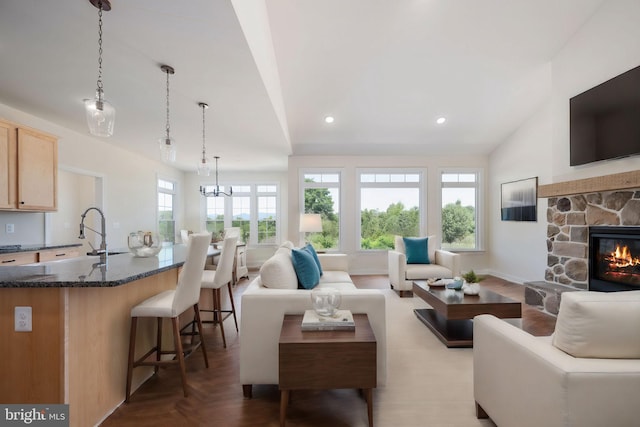 living room with sink, lofted ceiling, and a stone fireplace