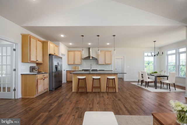 kitchen featuring a center island with sink, wall chimney exhaust hood, light brown cabinets, sink, and stainless steel refrigerator with ice dispenser