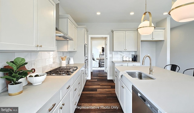 kitchen featuring white cabinets, stainless steel appliances, sink, backsplash, and hanging light fixtures