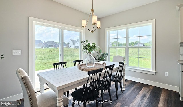 dining room featuring a healthy amount of sunlight, dark hardwood / wood-style flooring, and a chandelier