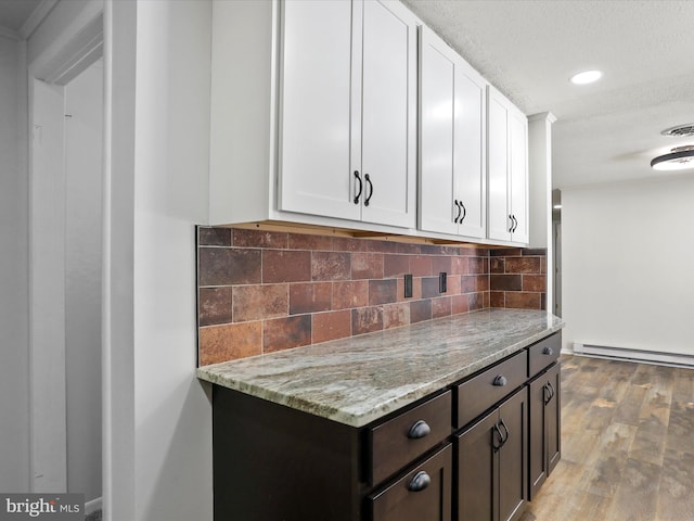 kitchen featuring light stone countertops, light hardwood / wood-style floors, a baseboard heating unit, white cabinets, and dark brown cabinetry