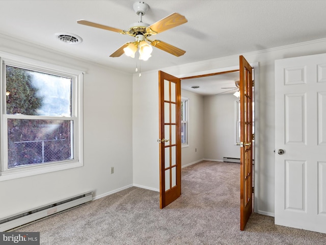 carpeted spare room featuring french doors, baseboard heating, ceiling fan, and crown molding