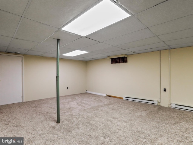 basement with a baseboard heating unit, a drop ceiling, and carpet