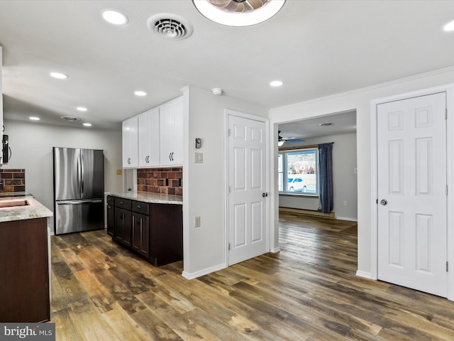 kitchen featuring white cabinets, ceiling fan, tasteful backsplash, dark brown cabinetry, and stainless steel fridge