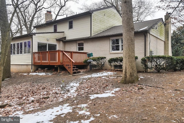 snow covered house featuring a sunroom and a wooden deck