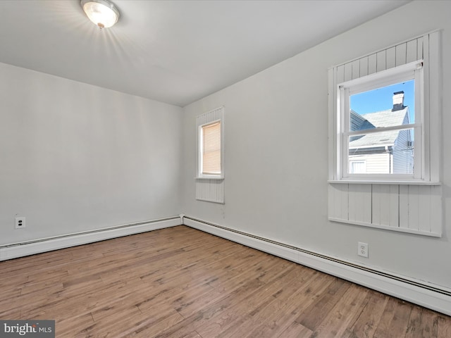 spare room featuring a baseboard heating unit and light wood-type flooring