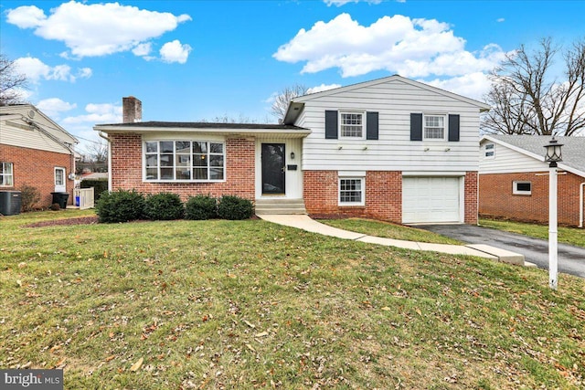 split level home with a front yard, a garage, and central air condition unit