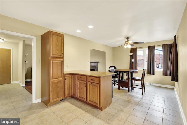 kitchen with ceiling fan, light tile patterned flooring, light stone countertops, and kitchen peninsula