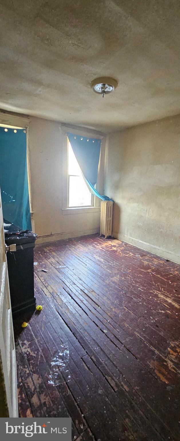 unfurnished room with radiator, a textured ceiling, and hardwood / wood-style flooring